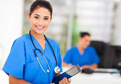 Female nurse wearing blue scrubs smiling